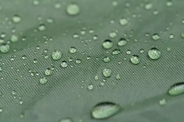 Close-up of rain beading on green waterproof fabric