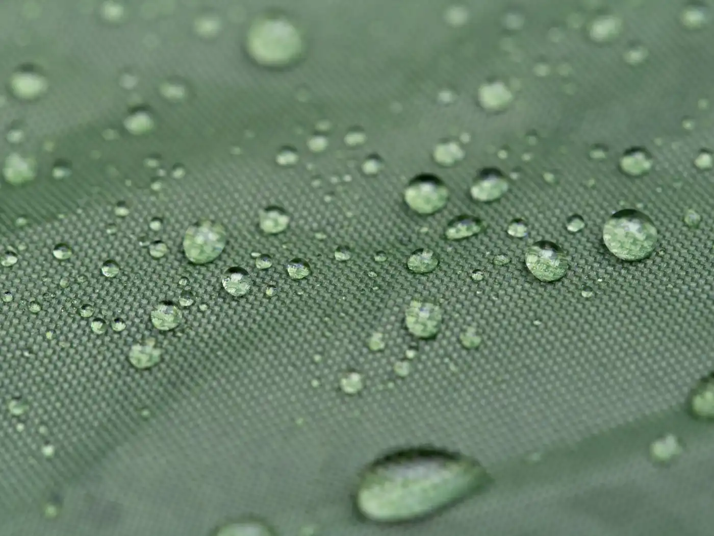 Close-up of rain beading on green waterproof fabric